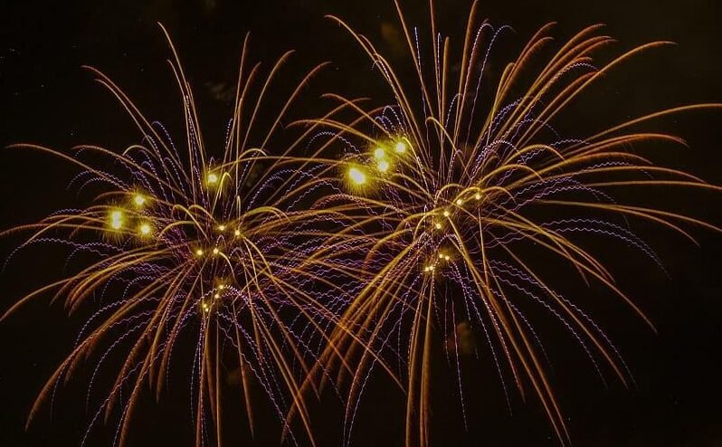 A vibrant and synchronized pyrotechnic display captured at night by a professional fireworks company for corporate events 